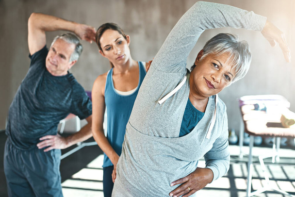 Physical therapy is great for improving overall flexibility. a senior man and woman working out with the help of an instructor - Fotografie, Obrázek