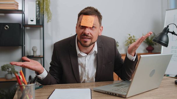 Businessman in suit with inscription note text Loser on forehead working on laptop loses becoming surprised sudden lottery results, bad news, fortune loss, fail at office. Male freelancer business man - Foto, Imagen