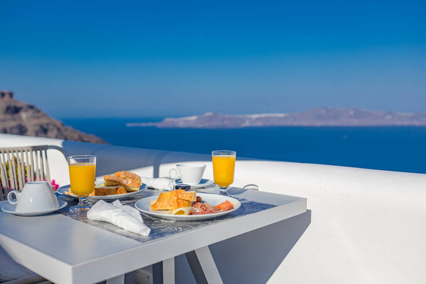 Breakfast time in Santorini in hotel. Luxury mood with fresh omelet and fruits with juice over sea view. Luxurious summer traveling holiday background. Happy relax vibes, couple morning closeup table - Photo, Image