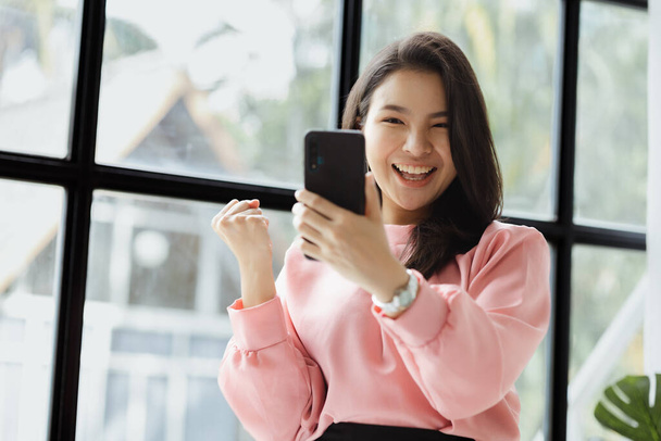 Asian women look at information on mobile phones and show joyful expressions. run by a young, talented woman. The management concept runs the company of female leaders to grow the company. - Photo, Image