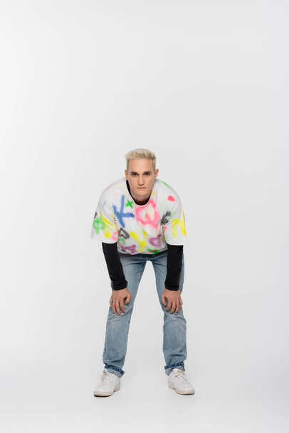 full length of blonde gay man in trendy clothes looking at camera on grey background - Foto, Bild