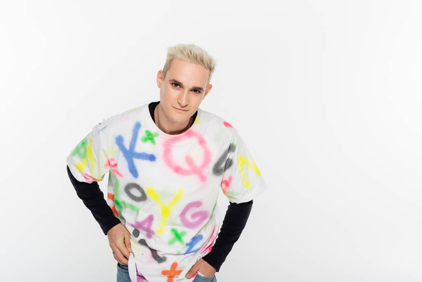 blonde gay man in stylish t-shirt looking at camera isolated on grey - Foto, Imagen