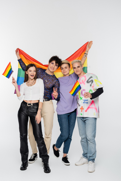 cheerful friends of diverse identity standing with lgbtq flags on grey background - Foto, Imagen