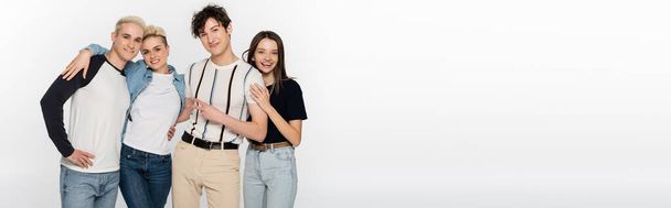happy and stylish friends embracing and looking at camera isolated on grey, banner - Foto, immagini