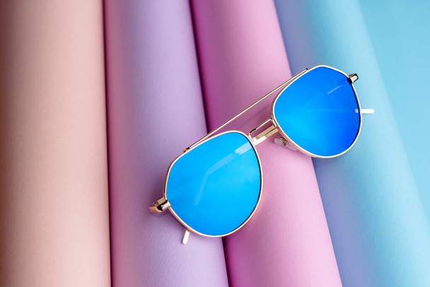 Fashion of Sunglasses with blue lens put on colorful paper background - Photo, image