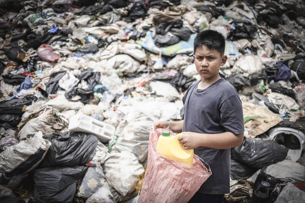  Маленький бедный индийский мальчик собирает пластиковые бутылки в мешок, чтобы заработать себе на жизнь.. - Фото, изображение