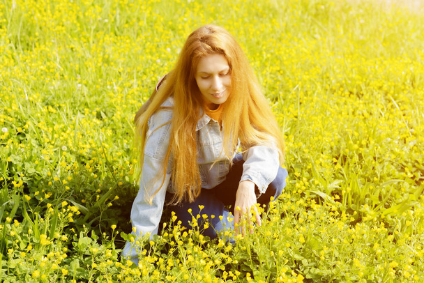 Женщина на желтом лугу Ранункулуса. Женщина сидит в поле среди жёлтых лютиков. - Фото, изображение