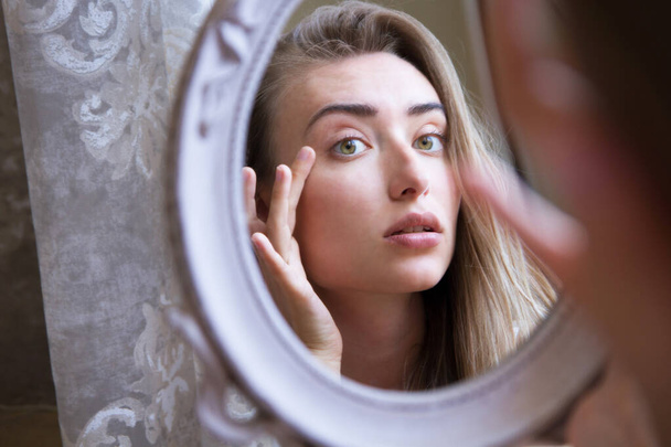 Азиатская кавказка девушка несчастная трогательная ее лицо взгляд на зеркало вблизи - Фото, изображение