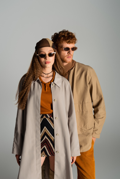 young and stylish couple in autumnal outfits posing isolated on grey - 写真・画像