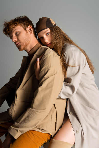 teenage girl with wavy hair hugging stylish and redhead boyfriend isolated on grey - Фото, изображение