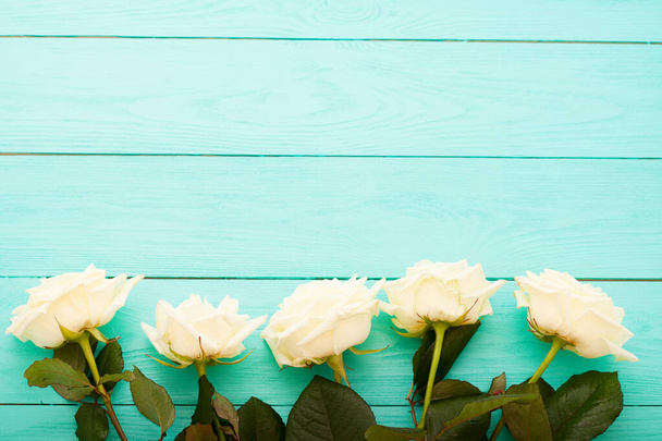 рамка из белых роз на синем деревянном фоне с копировальным пространством - Фото, изображение