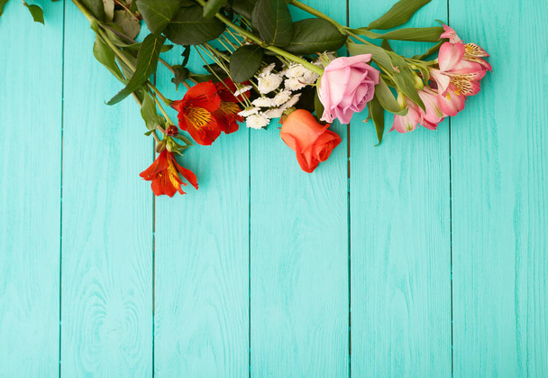Boeket bloemen op blauwe houten achtergrond. bovenaanzicht en kopieerruimte. - Foto, afbeelding