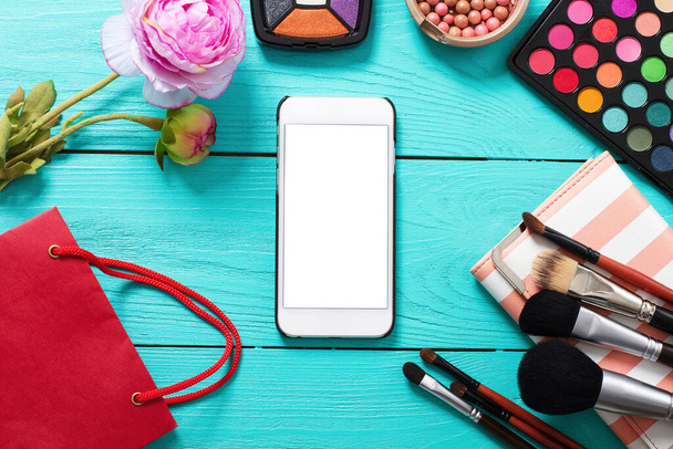 Keret kozmetikumok és üres mobil képernyő kék fa háttér. Felülnézet és másolás - Fotó, kép