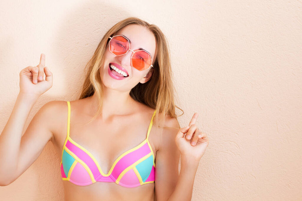 Pretty Emotional Young Woman In red Sunglasses Wearing Swimsuit Leaning Against Wall - Photo, Image