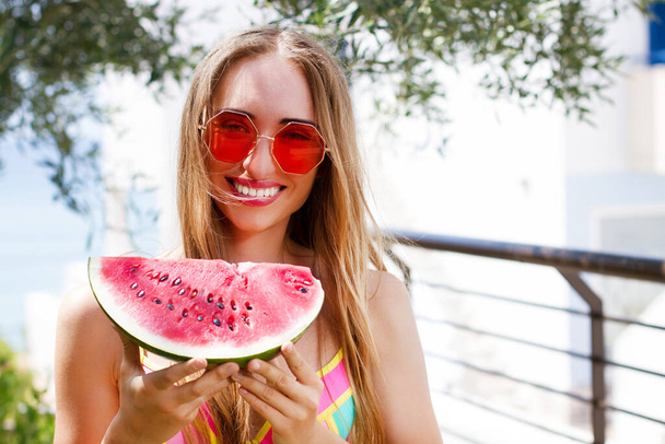 sexy girl in red sunglasses holds a cut watermelon in her hands. Happy Woman In Trendy Red Sunglasses copy space - Fotografie, Obrázek