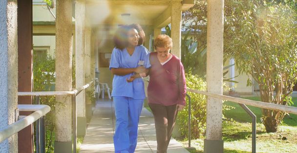 Médica africana que habla con mujeres mayores jubiladas en el patio del hospital. concepto de felicidad y jubilación. - Foto, Imagen
