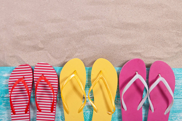 Sand copy space. Sand background top view. Multicolored beach flip flops - Valokuva, kuva