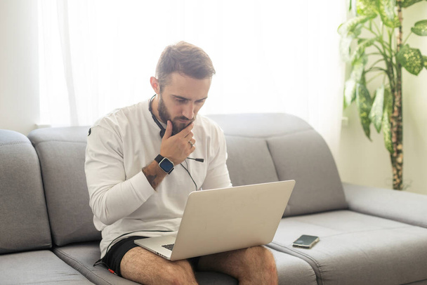 Nuori mies freelancer käyttäen kannettavaa tietokonetta opiskelu verkossa työskentelevät kotoa, onnellinen rento kaveri kirjoittamalla kannettavaan - Valokuva, kuva