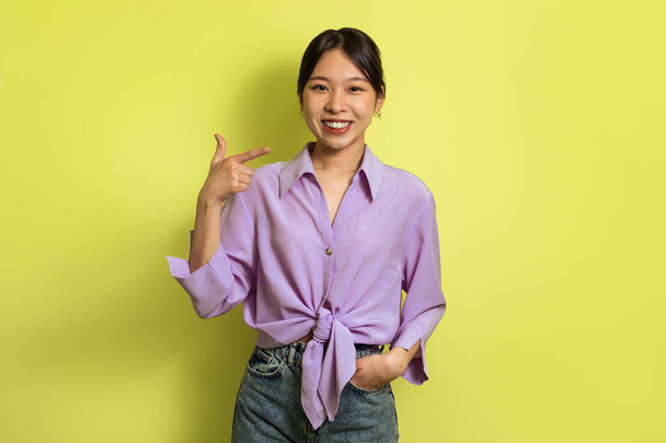 Look At Me. Cheerful Asian Lady Pointing Finger At Herself Smiling Looking At Camera Posing Standing Over Yellow Studio Background. I Choose Myself Concept - Fotó, kép