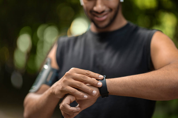 Clropped of black sportsman exercising in public park, setting fitness tracker before workout, checking heart rate, copy space, closeup. Modern technologies and sport concept - Photo, image