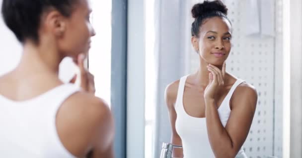 Beauty, face and woman with her health skincare looking at reflection on bathroom mirror in wellness portrait. Healthy, facial and young person doing cosmetic hygiene selfcare morning routine at home. - Footage, Video