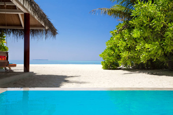 Ландшафт на острове Мальдив, роскошные водные виллы курорта с бассейном. Небо, океан и пляж с пальмовым фоном для летнего отдыха и путешествий. Роскошные путешествия. - Фото, изображение