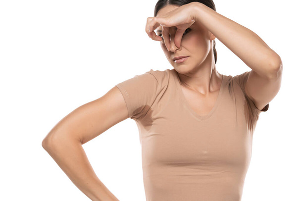 Young woman hand squeezing nose with odor sweating,Female smelling or sniffing her armpit,Bad smell - Foto, immagini