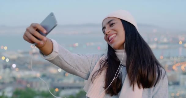 Fun woman taking selfies on phone for social media and making happy memory in city. Cool, funky and fashionable woman showing laughing, blowing kisses and streaming online with a mobile smartphone. - Filmati, video