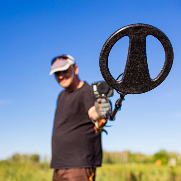 treasure hunter close-up with a metal detector, front and back background is blurred - Foto, Bild