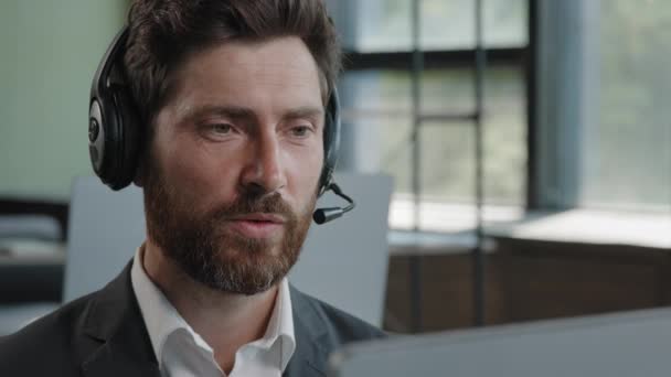 Serious Caucasian bearded businessman in headset headphones conference calling by webcam focused online teacher in video call teaching remote distant e-learning talk male agent helpline consultation - Felvétel, videó