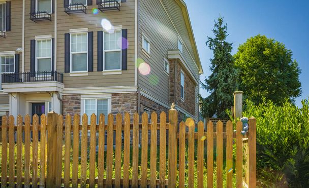 家の周りの素敵な木製の柵。緑の芝生と木製のフェンス。ストリートフォト、誰も、選択的フォーカス - 写真・画像