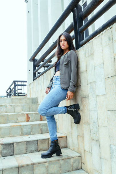 мода підліток латинська дівчина позує на міських сходах на відкритому повітрі в джинсах, чоботях і модельному піджаку
. - Фото, зображення