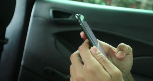 Closeup of young african black man typing on cellphone device in backseat of car - Πλάνα, βίντεο