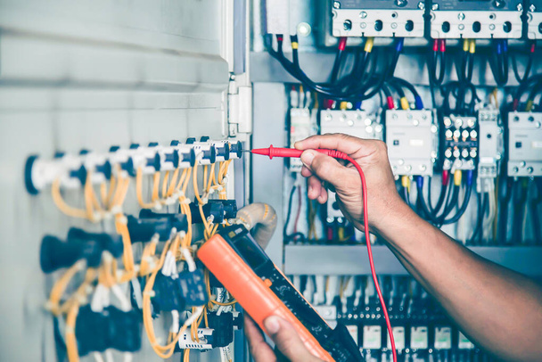 An electrical engineer is inspecting the operation of an electrical control cabinet. maintenance concept - Фото, изображение