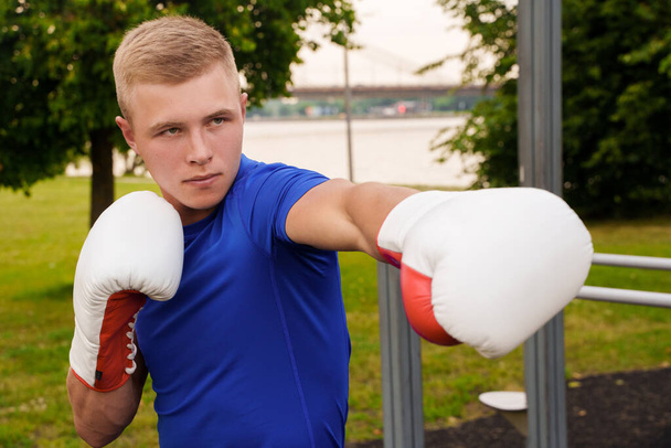 Shot of professional boxer dressed in sportswear exercising on urban sports ground in daytime. - Foto, afbeelding