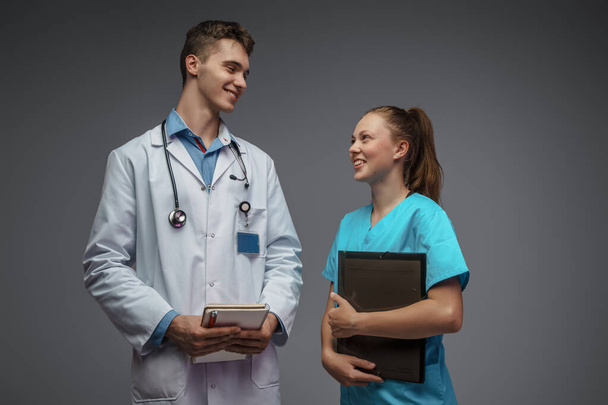 Фото медсестри з папкою і лікарем, одягнені в біле лабіринтове пальто, дивляться один на одного
. - Фото, зображення
