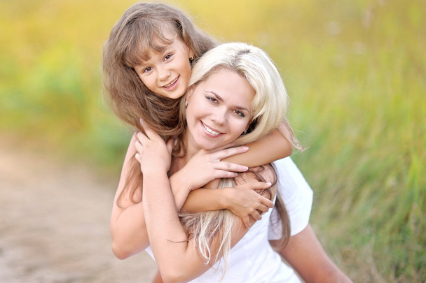 Young mother hugging her daughter in summer nature - Photo, image