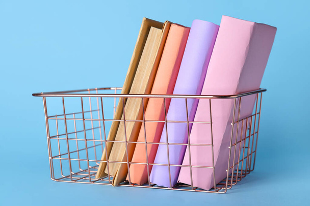 Pink metal basket with books on blue background - Foto, Imagen