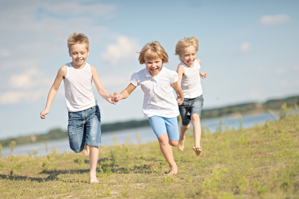 three children playing on meadow in summer - Foto, afbeelding