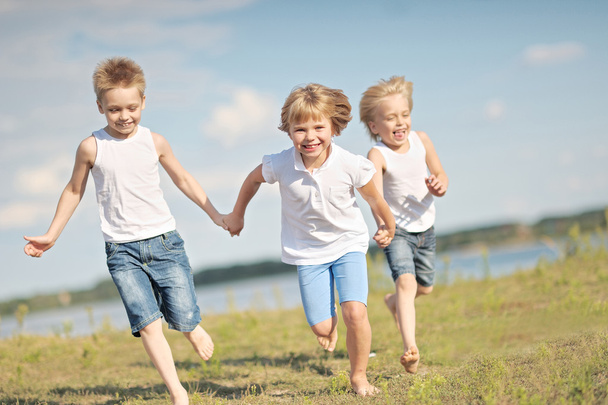 three children playing on meadow in summer - Foto, afbeelding