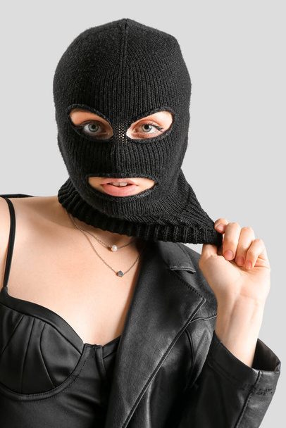 Portrait of young woman in balaclava against light background - Foto, imagen