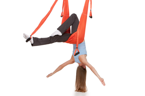 Young woman doing anti-gravity aerial yoga in hammock on a seamless white background. - Foto, imagen