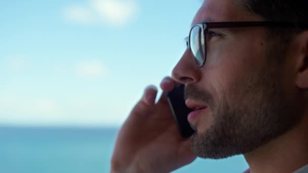 Closeup man talking phone ocean view. Unshaven entrepreneur looking panoramic window. Happy manager ceo calling speaking cellphone on business trip. Thinking businessman holding mobile conversation - Imágenes, Vídeo