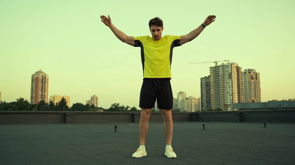 Young sportsman working out on roof of building in evening  - Foto, Imagen