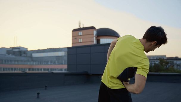 Young brunette sportsman working out on roof in evening  - Foto, Bild