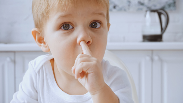 close up of toddler boy picking nose while looking at camera at home - Foto, Imagem