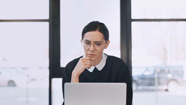 серйозна бізнес-леді в окулярах і формальне мислення одягу біля ноутбука в офісі
 - Фото, зображення