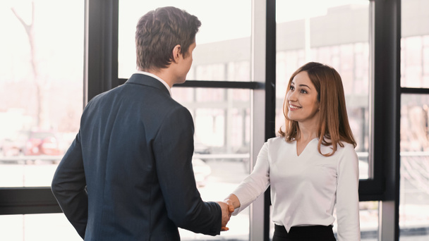 businessman shaking hands with cheerful woman after job interview - Foto, Imagen
