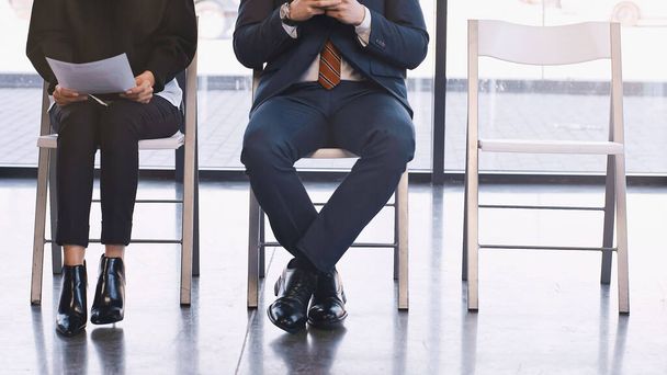 cropped view of woman with resume waiting for job interview near man in office - Foto, Bild
