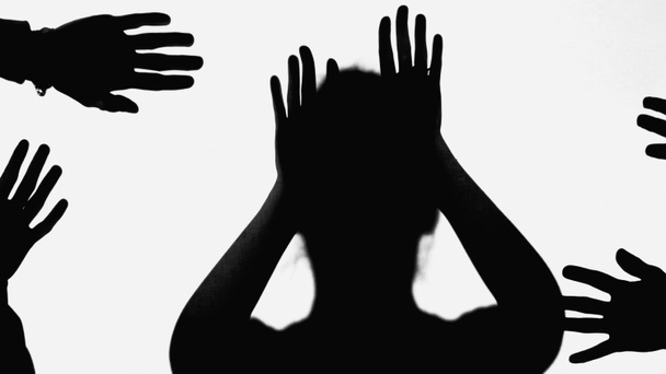 black shadow of bullied woman gesturing near hands of people isolated on white - Фото, изображение